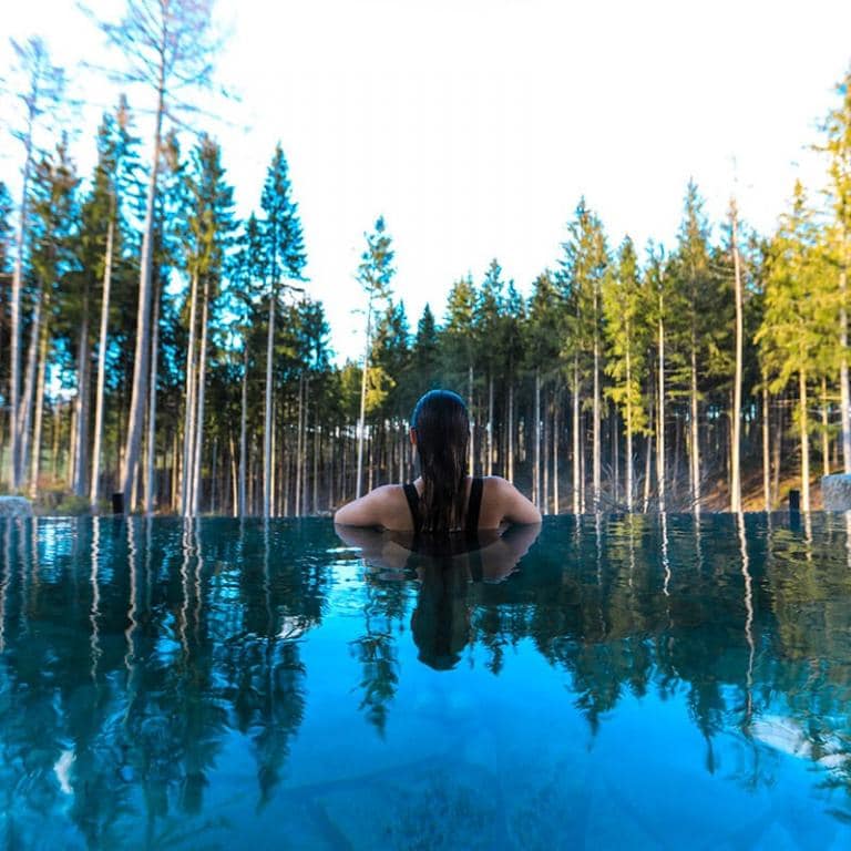 Une femme profite d'une piscine avec une vue sur la forêt